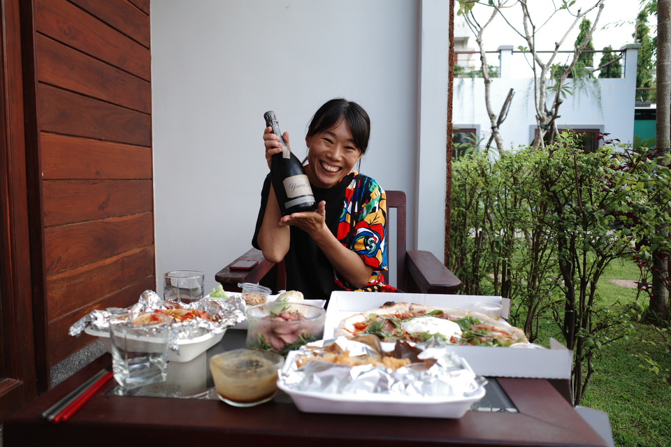 クメールハウスのバルコニーでシャンパンを飲む30代女性